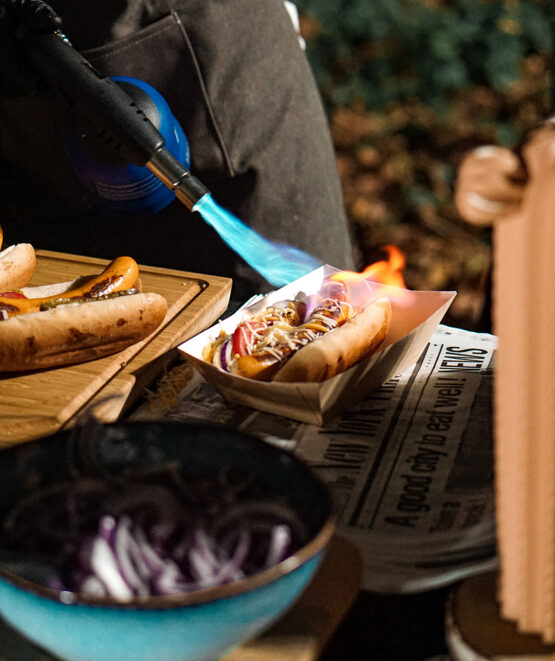 Chef grilling cheese on a hotdog at Taste Corner’s scenographic hotdog station during a catered event in South Florida