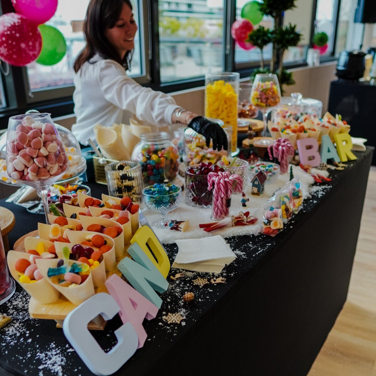 Candy station with host handing out sweets at Taste Corner’s scenographic Christmas buffet during a festive event in South Florida