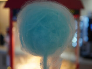 Guest holding a blue cotton candy at Taste Corner’s scenographic station during a festive event in South Florida