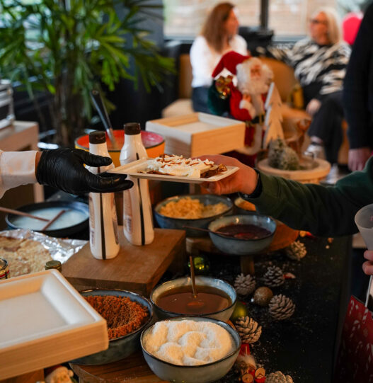 Chef handing a gourmet crêpe topped with whipped cream to a guest at Taste Corner’s scenographic station in South Florida