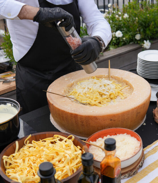 Chef grating truffle over pasta served in a parmesan wheel at Taste Corner’s live station in South Florida