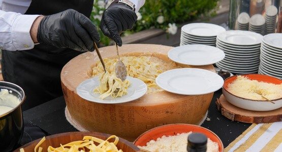 Chef preparing pasta in a parmesan wheel with Italian scenography at Taste Corner’s live station in South Florida