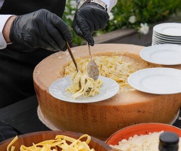 pasta-station-parmesan-wheel-italian-scenography-live-chef-event-catering-miami Chef preparing pasta in a parmesan wheel with Italian scenography at Taste Corner’s live station in South Florida