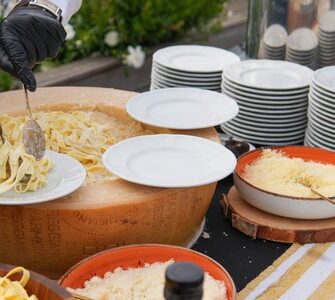 Chef preparing pasta in a parmesan wheel with Italian scenography at Taste Corner’s live station in South Florida