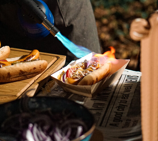 Chef grilling cheese on a hotdog at Taste Corner’s scenographic hotdog station during a catered event in South Florida