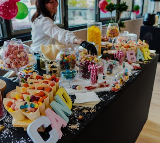 Candy station with host handing out sweets at Taste Corner’s scenographic Christmas buffet during a festive event in South Florida