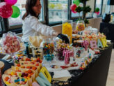 Candy station with host handing out sweets at Taste Corner’s scenographic Christmas buffet during a festive event in South Florida