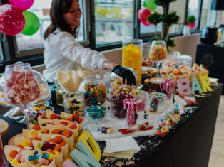 Candy station with host handing out sweets at Taste Corner’s scenographic Christmas buffet during a festive event in South Florida