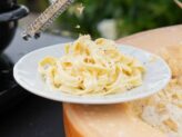 Chef grating truffle over pasta served in a parmesan wheel at Taste Corner’s live station in South Florida