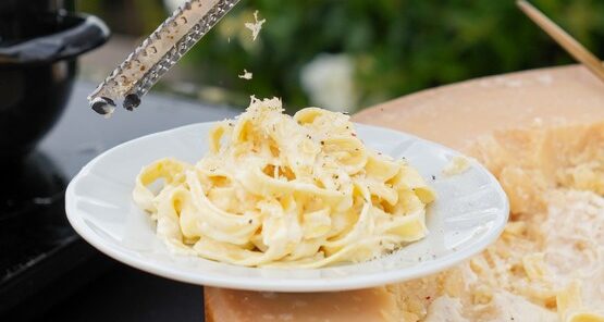 Chef grating truffle over pasta served in a parmesan wheel at Taste Corner’s live station in South Florida